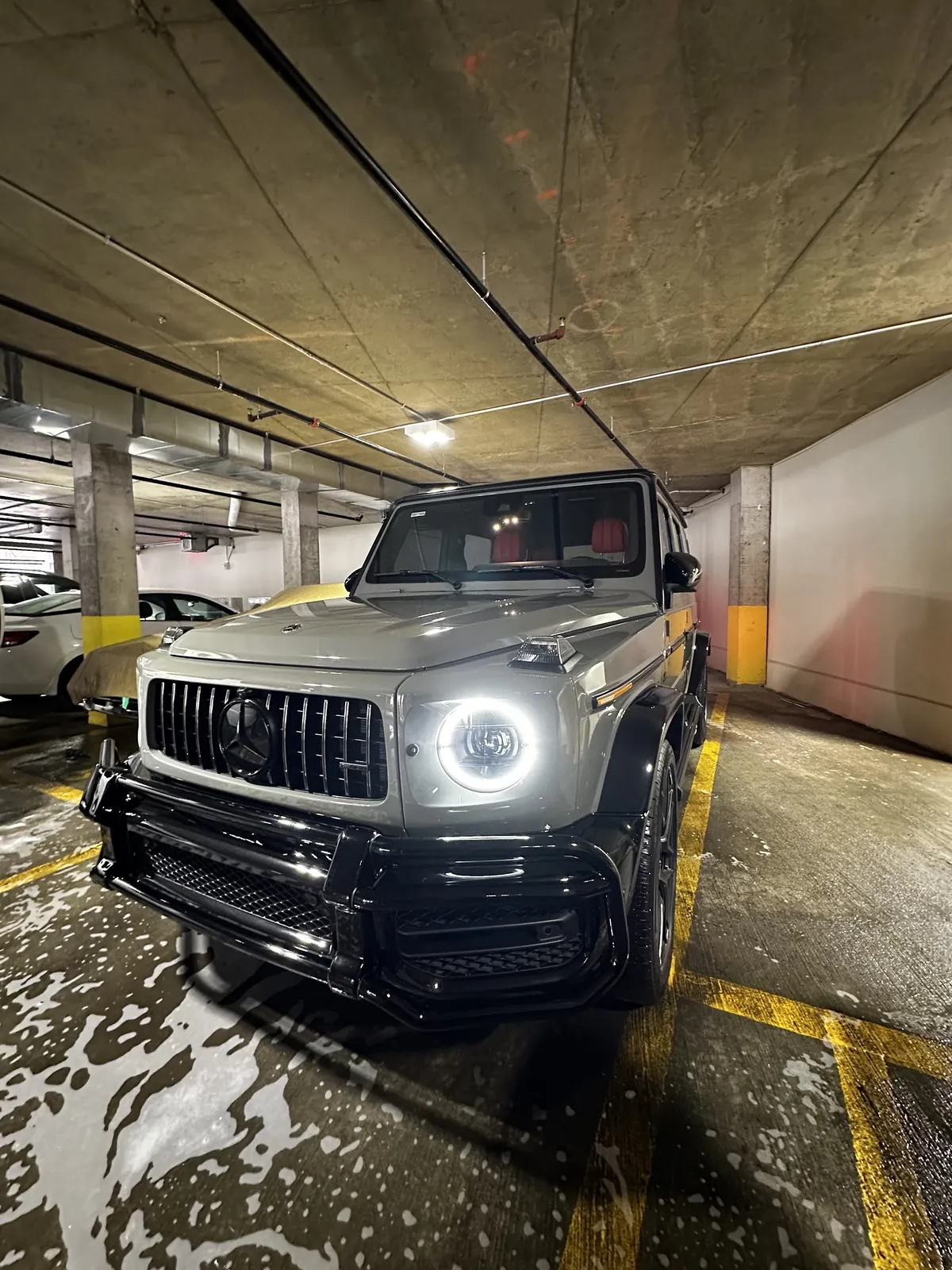 Gray Mercedes G-Wagon with red leather seats, freshly detailed in a parking garage