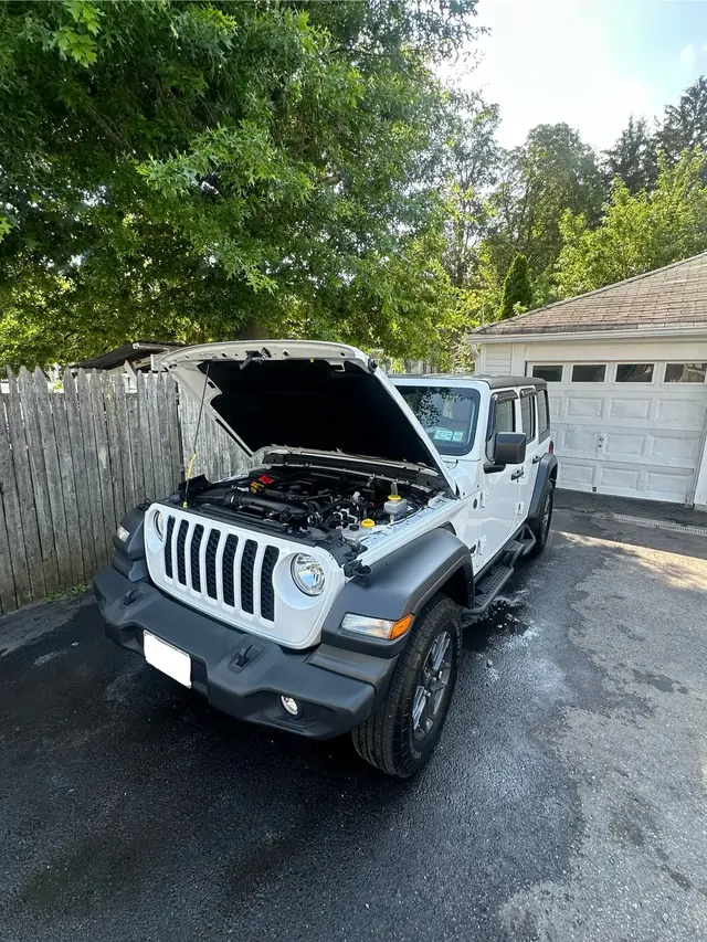 White Jeep Wrangler with the hood open for an engine bay detail